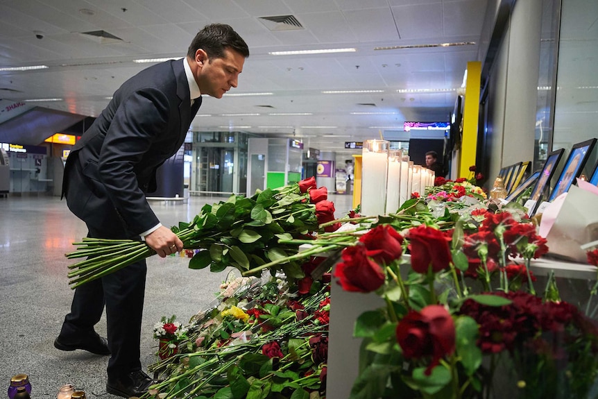 Ukrainian President Volodymyr Zelenskiy lays flowers at a memorial for Ukrainian Airlines flight crew.