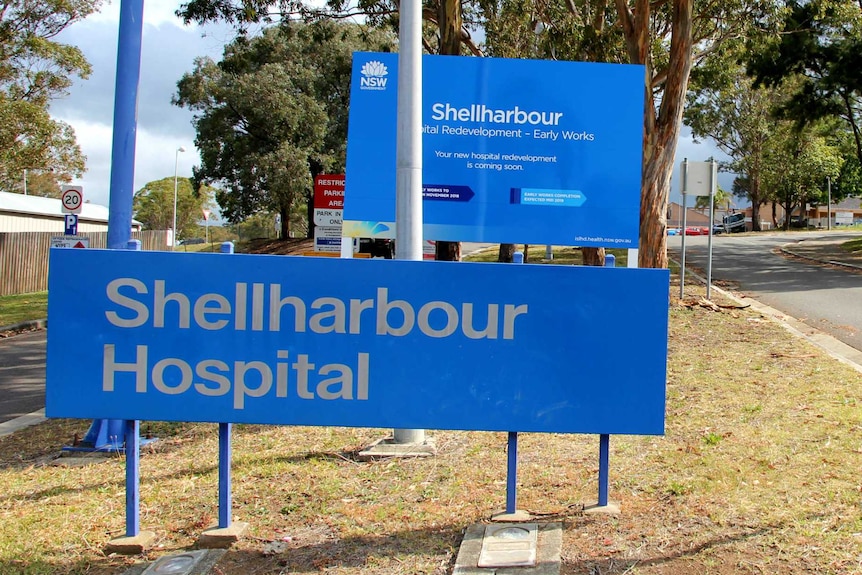 A blue sign with the name of the hospital - Shellharbour Hospital - at the front of the facility.