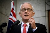 Close up shot of Malcolm Turnbull speaking with Australian flag in background