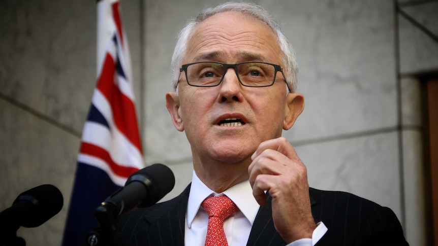 Close up shot of Malcolm Turnbull speaking with Australian flag in background