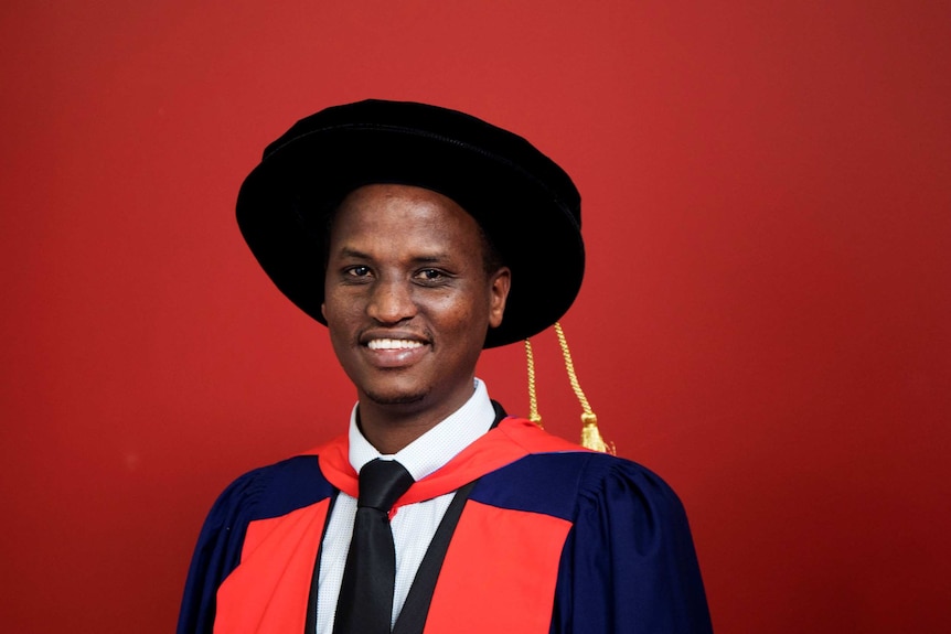 A young-looking man of African background wearing a graduation hat and gown.