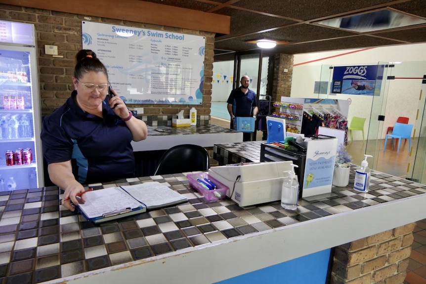 A woman answers a phone at the swim school front desk