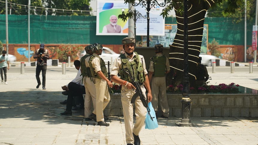 A group of guards walk around a square holding guns.