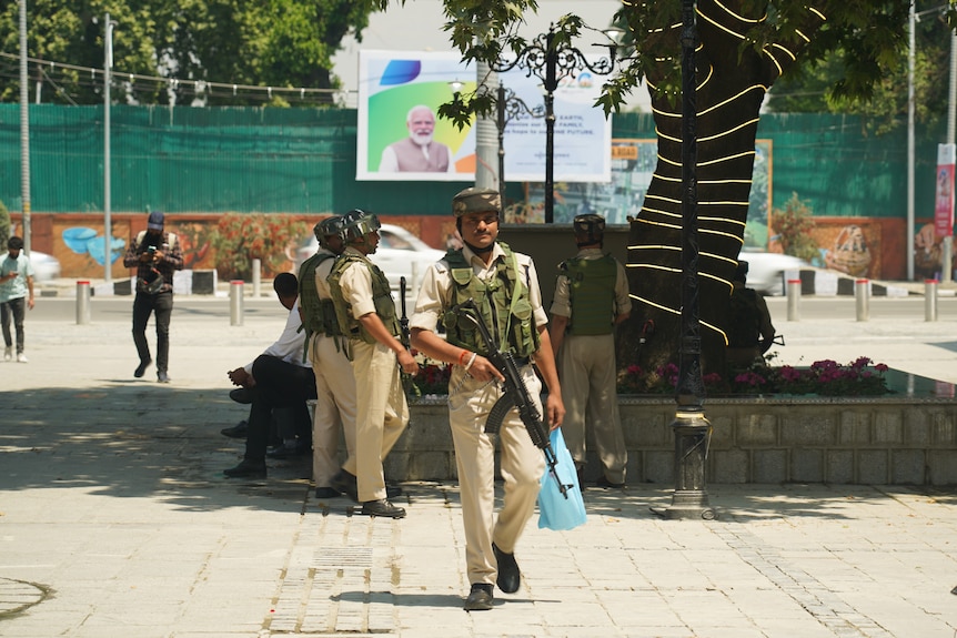 A group of guards walk around a square holding guns.