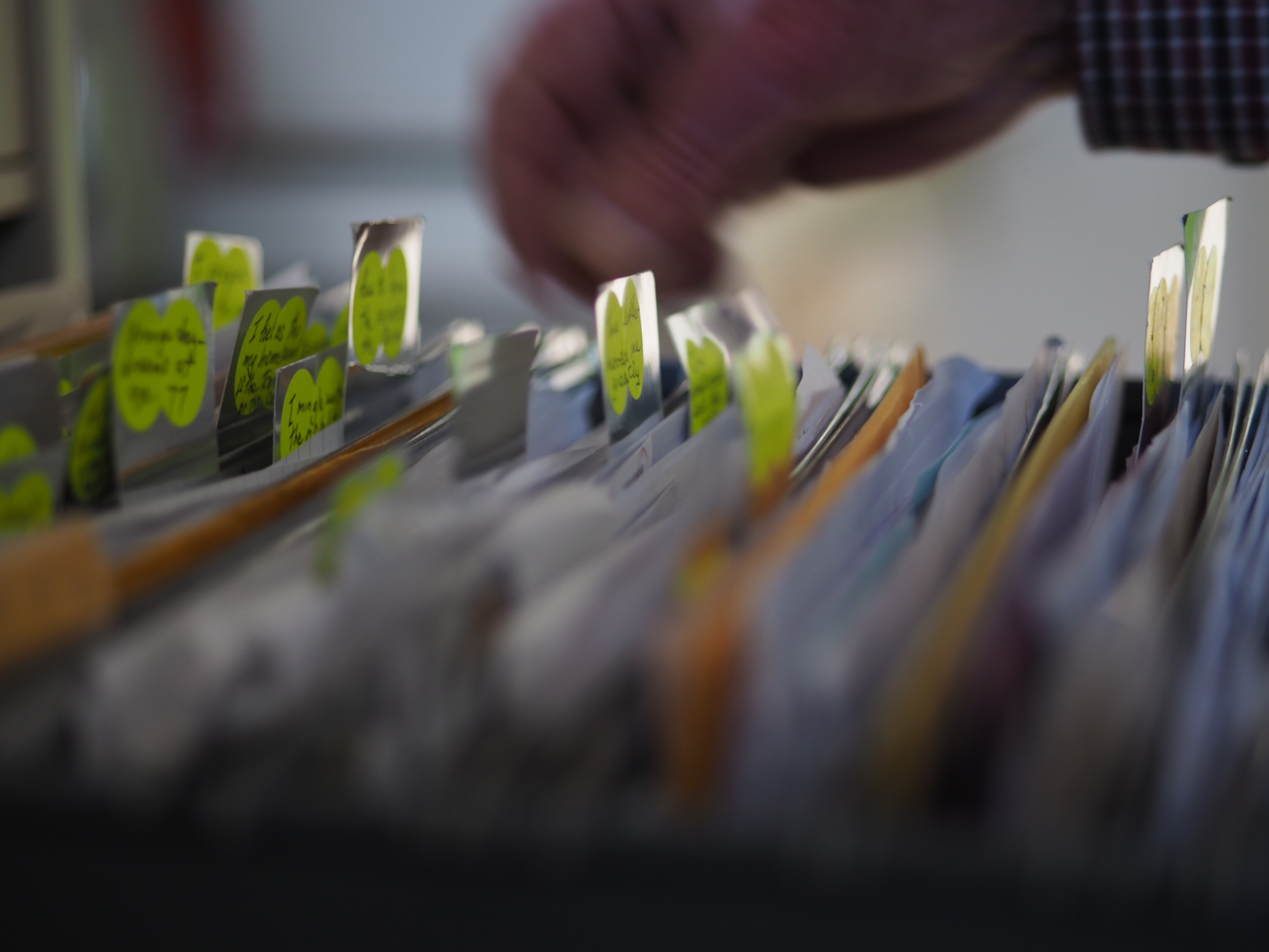 Un hombre hojea páginas de cartas, ensayos y manuscritos en un archivador.