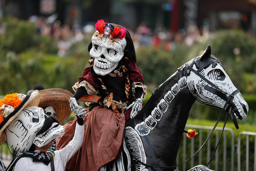A person in a skeleton costume rides a dark coloured horse.