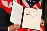 US President Donald Trump shows the document that he and Kim Jong-Un signed.