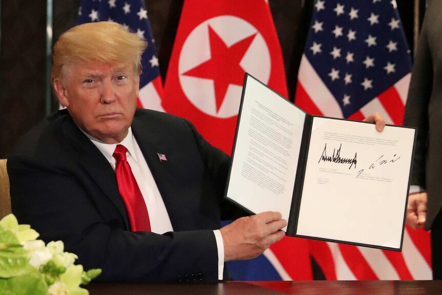 US President Donald Trump shows the document that he and Kim Jong-Un signed.