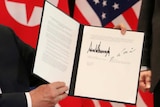 US President Donald Trump shows the document that he and Kim Jong-Un signed.