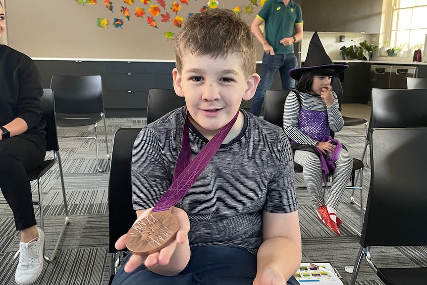A child holds a bronze Olympic medal.