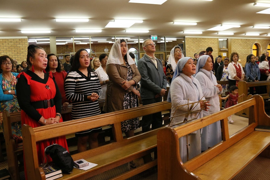 People standing inside a church sing.