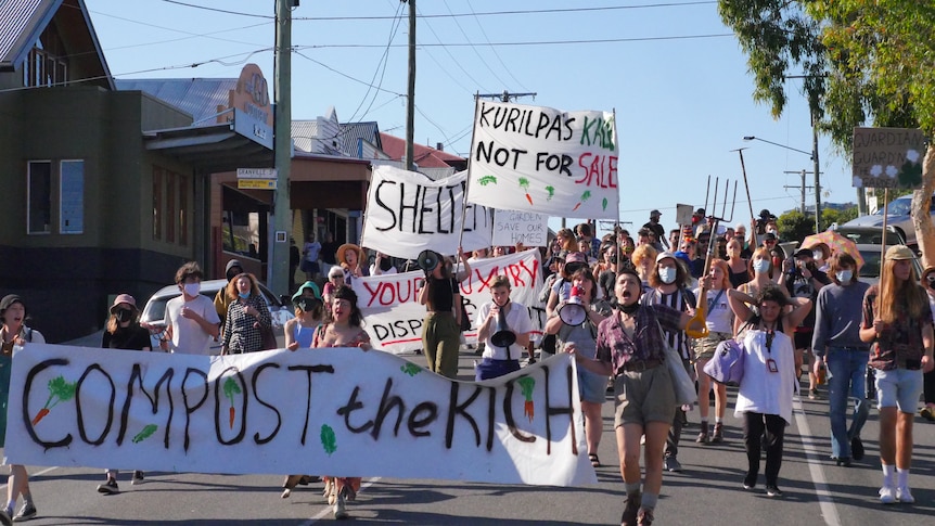 A small group of protesters, some with pitchforks, march through West End.