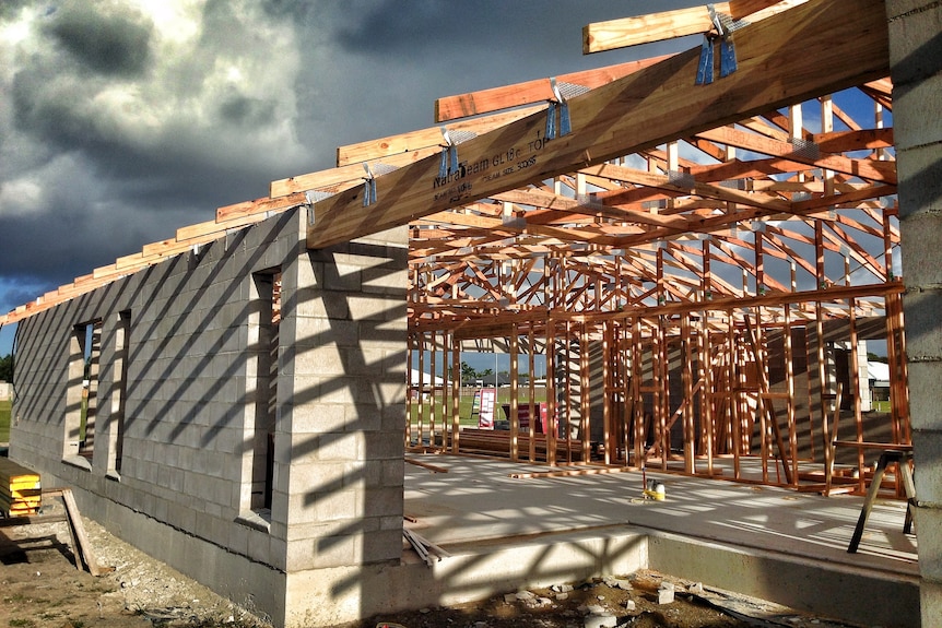 A home under construction with a timber frame and one external brick wall.