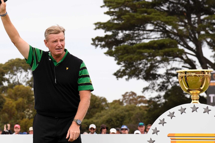 Ernie Els doffs his cap to the crowd as he walks past the Presidents Cup trophy
