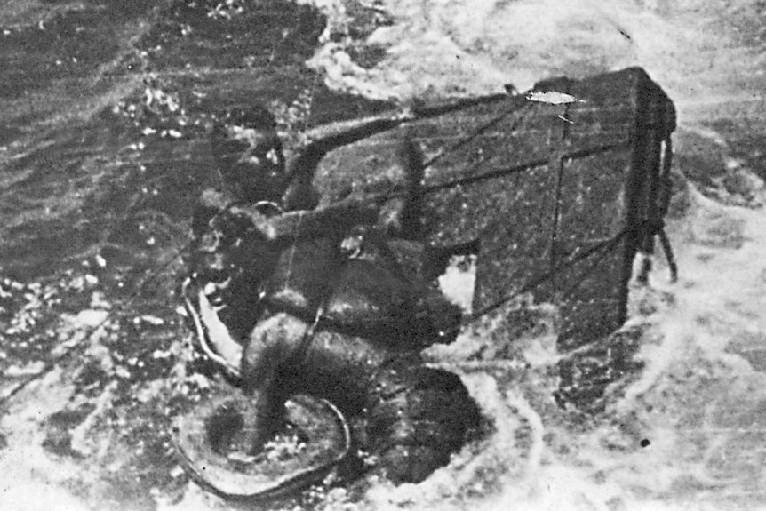 Men holding onto to wreckage in the ocean.