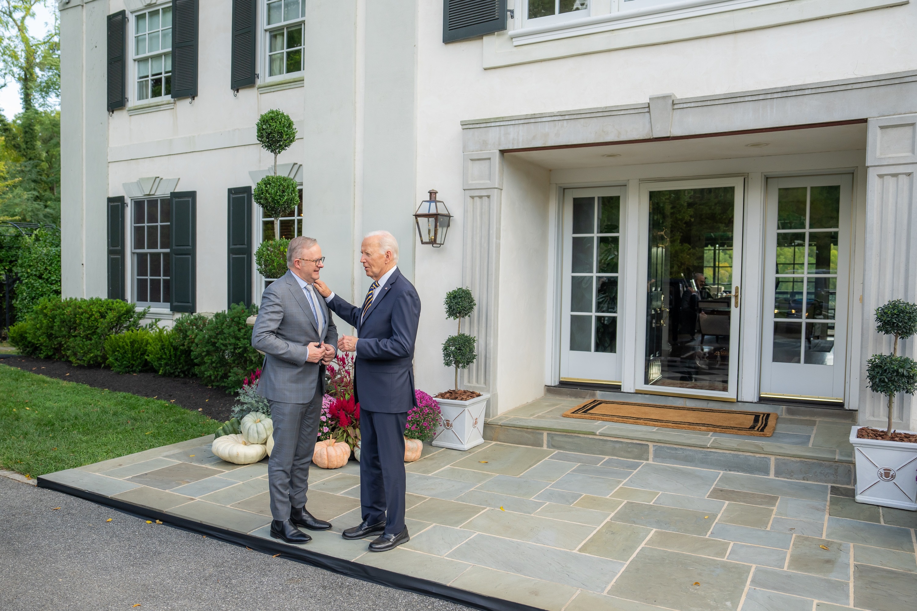 Anthony Albanese and Joe Biden stand out front of a grand white building, with Biden placing a hand on Albanese's shoulder.