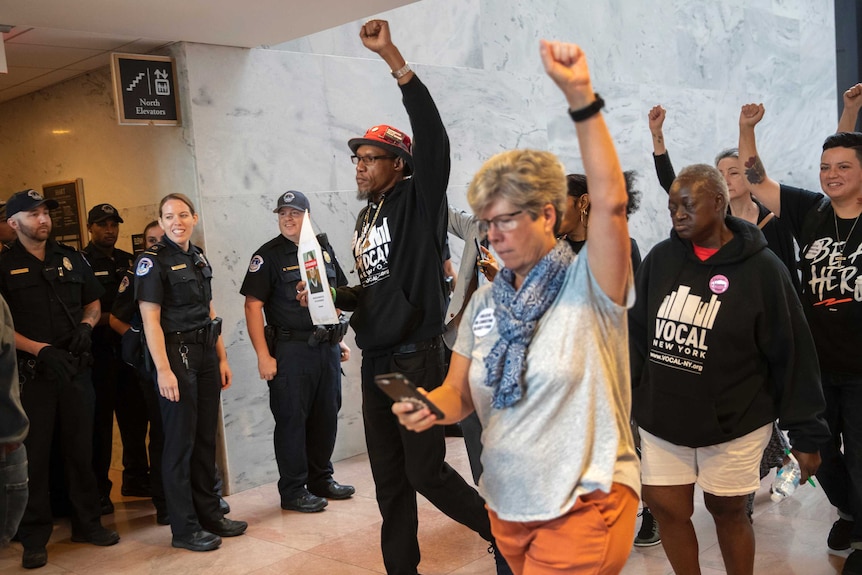 Protesters opposed to Brett Kavanaugh hold their fists up in the air