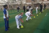Young girls play indoor cricket