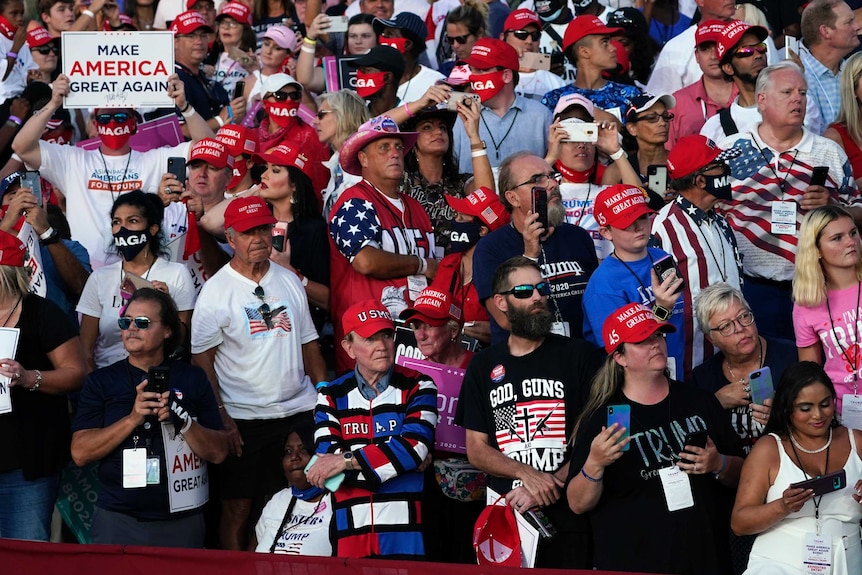 A crowd of Trump supporters in Maga hats, with only a few people in face masks
