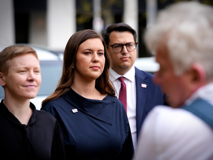 Brittany Higgins walking alongside another woman, with a man walking behind her.