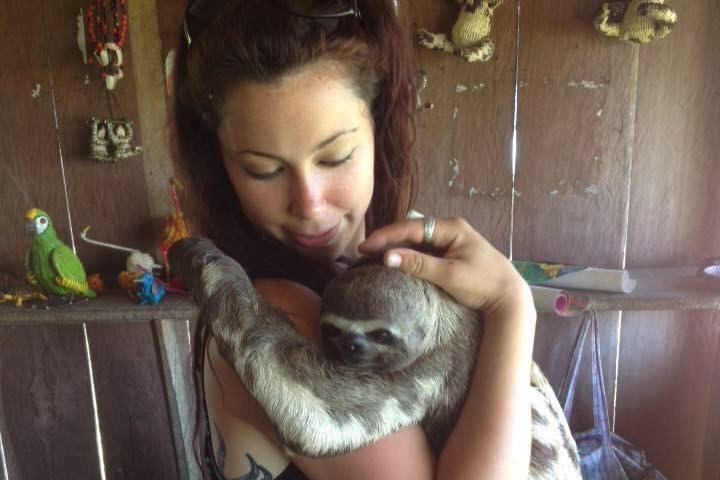 A young woman holding a sloth.