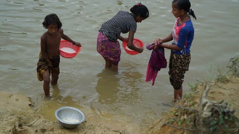 Refugees wash rice in a stream that runs through camp.