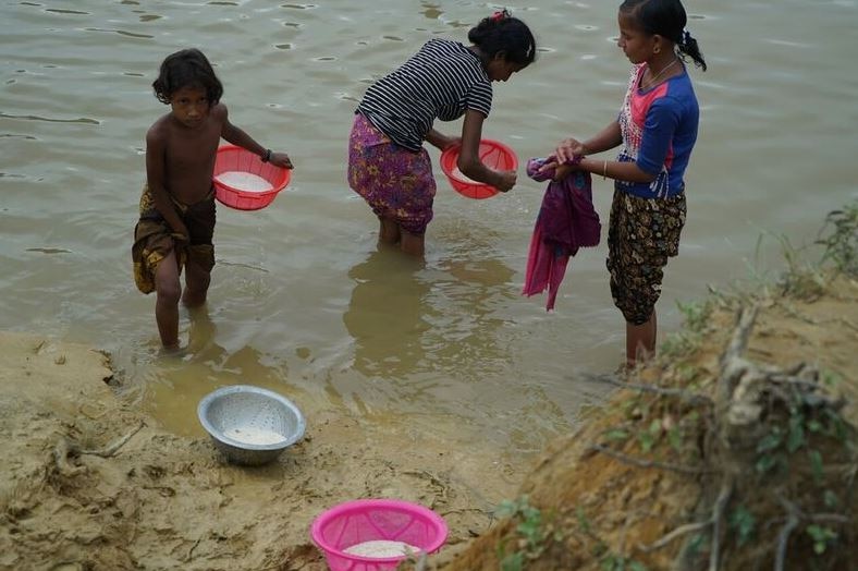 Refugees wash rice in a stream that runs through camp.