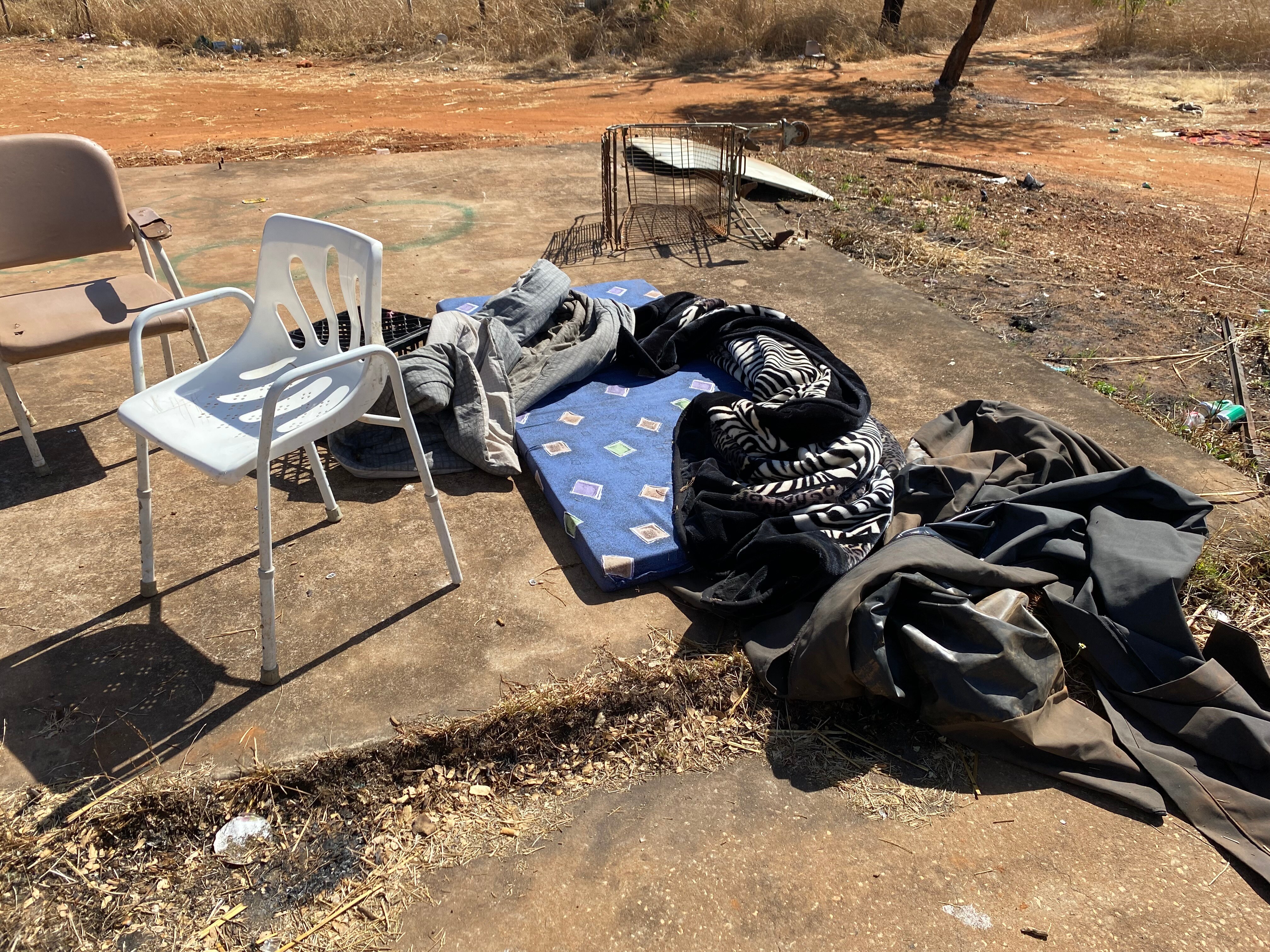 chairs, a mattress and bedding on a concrete slab