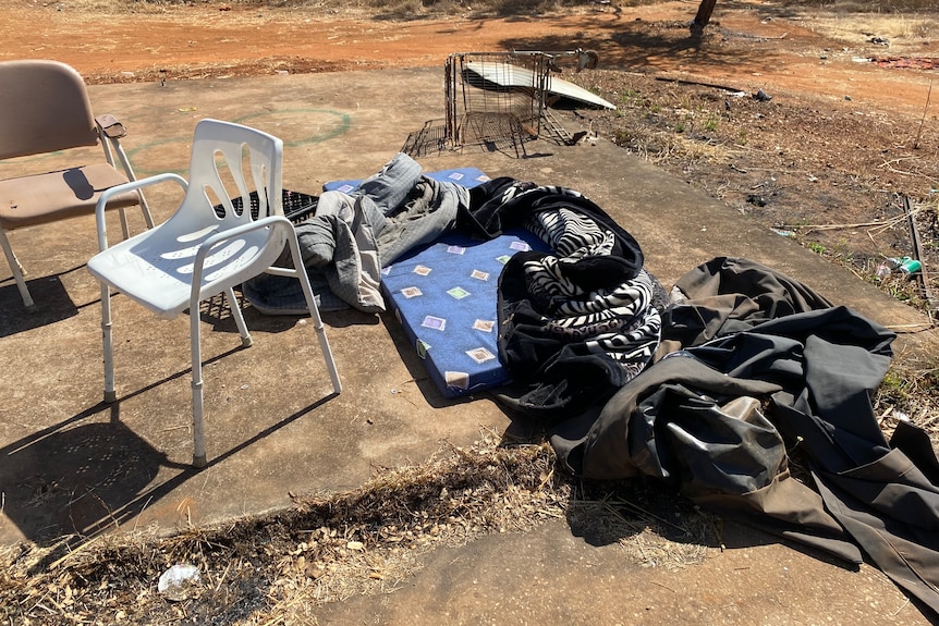 chairs, a mattress and bedding on a concrete slab