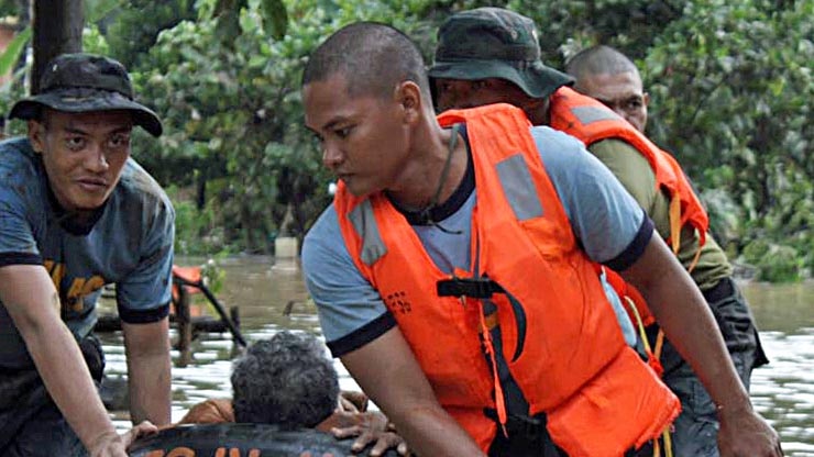 Philippine police rescuers use a rubber boat to evacuate a resident after flash floods.