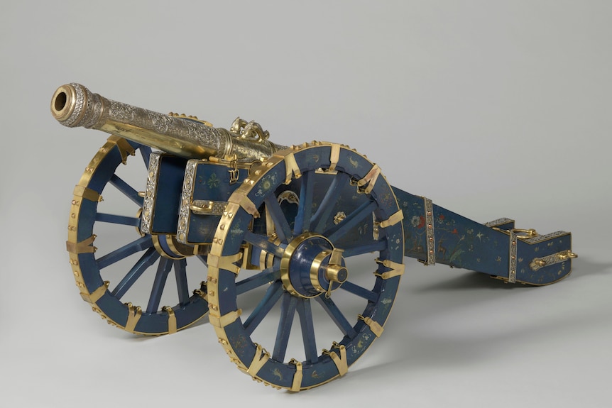 A gold decorated historical cannon, with a blue inlay 