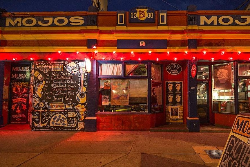 The exterior of Mojos bar in Fremantle at night with warm lighting and a dark sky.