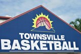 A outdoor sign that reads Townsville Basketball with a palm tree frond emerging in the background.