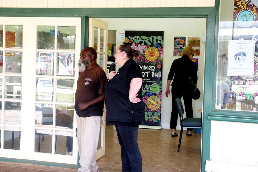 A man and a woman stand in a doorway talking.