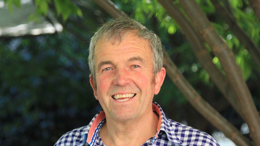 smiling man in front of trees