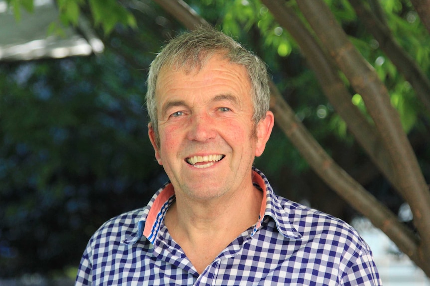 smiling man in front of trees