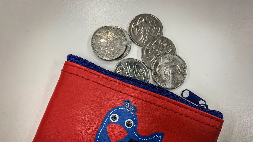 A red purse with coins coming out of the top of it.