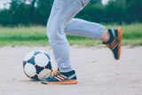 A child kicking a soccer ball.
