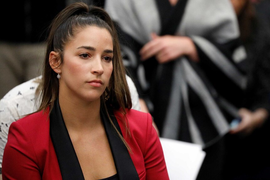 Aly Raisman sits in a courtroom with a serious look on her face.