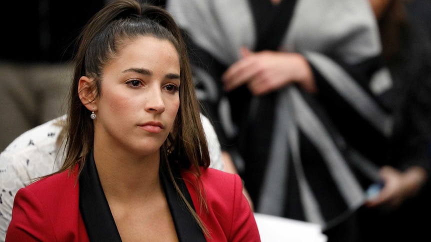 Aly Raisman sits in a courtroom with a serious look on her face.