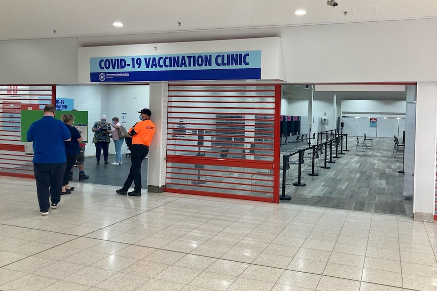 People line up to get into a building with a sign above them that read COVID-19 vaccination clinic. 
