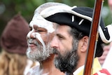 Close-up of faces of Aboriginal man with white paint on his face next to a Caucasian man wearing British navy uniform