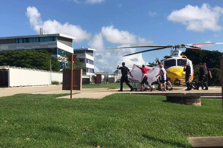 Paramedics wheel a man away from a medivac helicopter toward a hospital