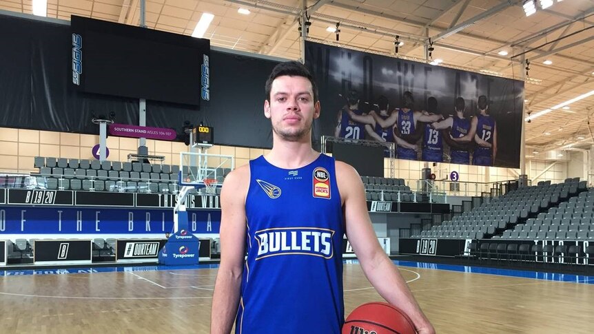 Jason Cadee looks at the camera while holding a basketball.