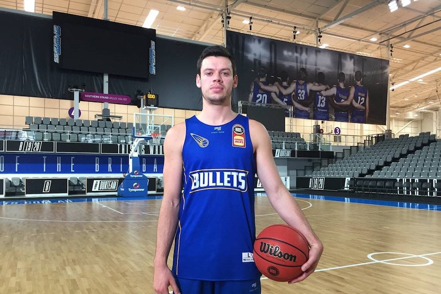 Jason Cadee looks at the camera while holding a basketball.