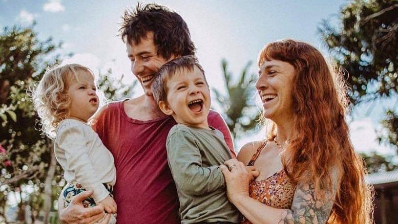 Man and woman holding two young children, one laughing and one not smiling