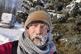 A man in a beanie with frozen eyelashes and beard