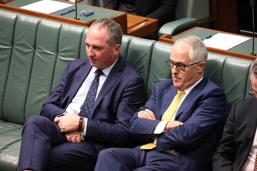 Barnaby Joyce, with his legs crossed and hands folded in his lap, next to Malcolm Turnbull, with arms folded across his chest.