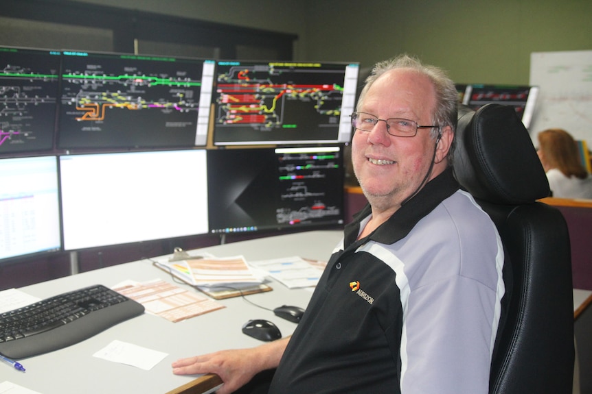Aurizon network controller Robbie Ward sits in front of his computer screen with the rail network on screen.