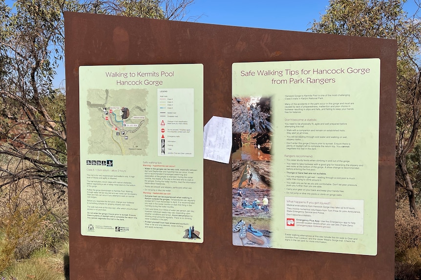 A sign for Karijini National park with a piece of paper lodged inbetween